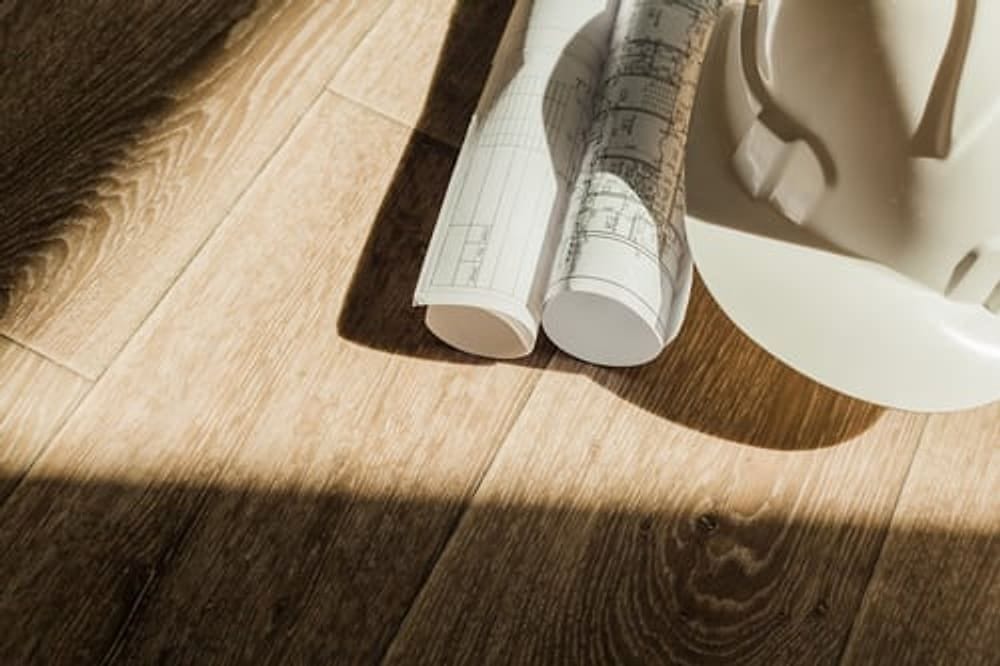 Wood-look plank flooring with construction plans laid out, installed by G&I B Construction